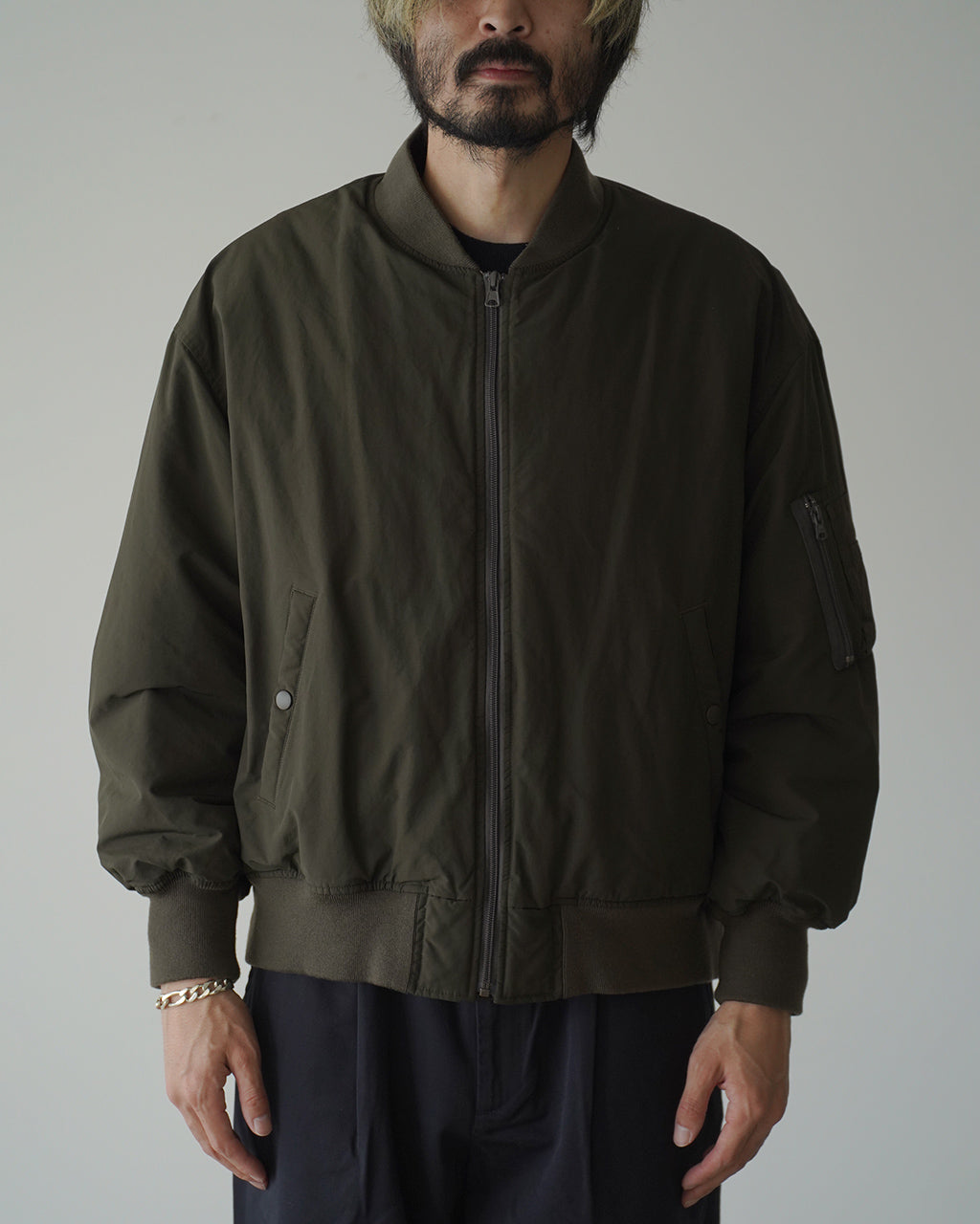 オリーブカラーのWeather Flight Jacketを正面から着用している男性モデル。ジップ開閉式で、ポケットや袖のディテールが見えるジャケットのシルエットとリブ仕様の裾が特徴。