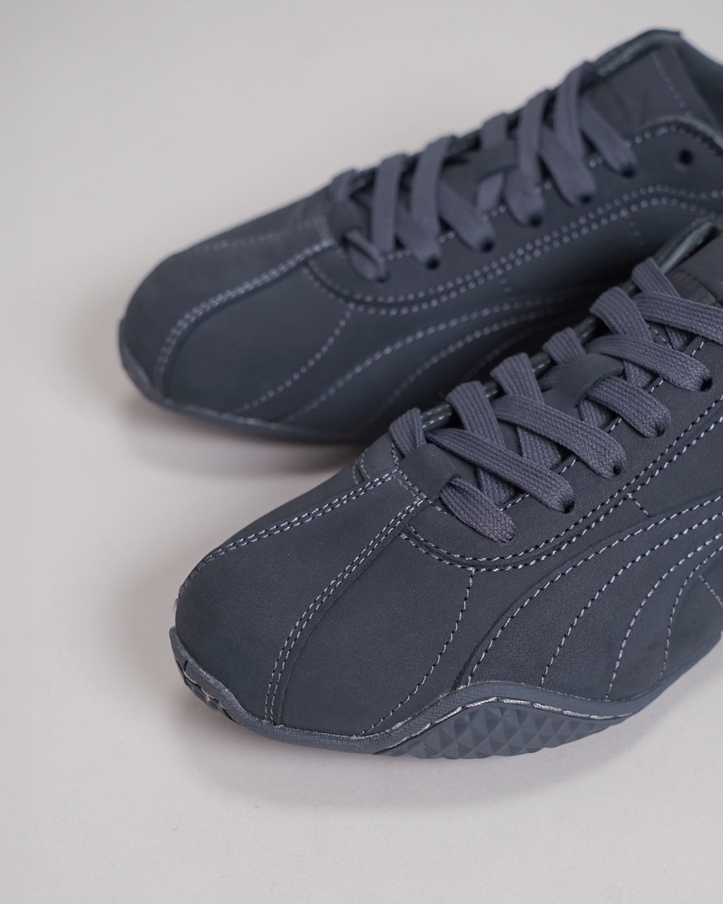 PUMAのダークネイビー系スニーカー。アップで刺繍ステッチが映える滑らかなレザー風素材と、立体的な靴紐が特徴的な前方ショット。