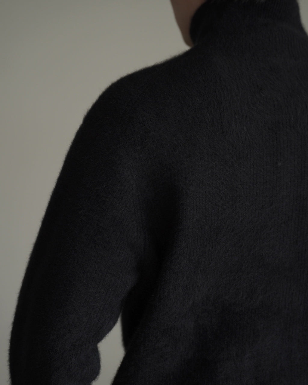 ブラックのFox Cashmere Zip-Up Sweaterの背面近く、柔らかな毛足の質感が強調されたニット。高密度な畦編みの縞模様が見えるシルエットのディテールショット。
