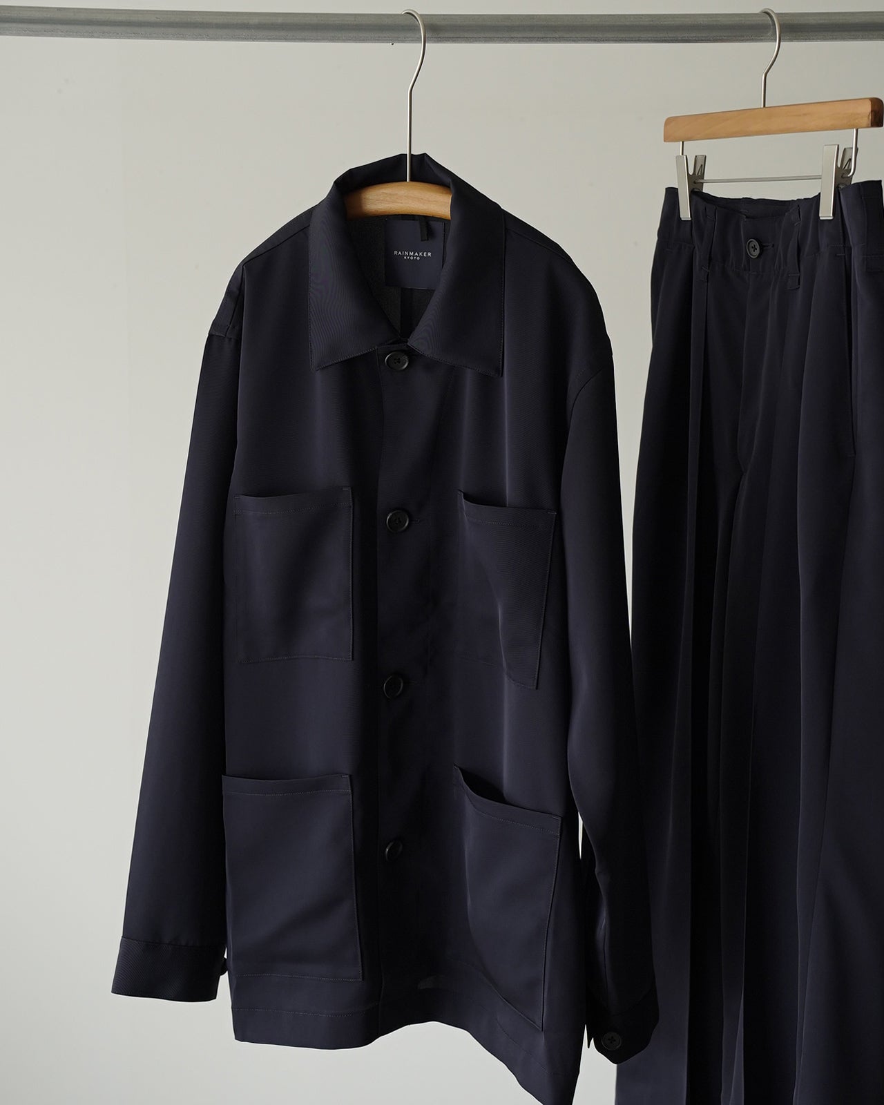 深いネイビーカラーのSUPPLE WORK SHIRT RM262-016。前身頃はボタン留めで大きめポケットが左右に配され、背面は裾に向かって緩やかに広がるシルエットがわかる撮影。生地の滑らかな光沢感が際立つディテール写真。