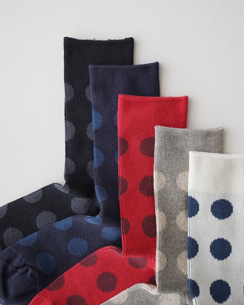 ROTOTO PORTHOLE DOT SOCKSのドット柄ソックス。黒・ネイビー・赤・グレーなど複数色のポップな縞模様が並ぶ、つま先をつなぐリンキング技法の縫製を特徴とするベーシックな長さの靴下です。