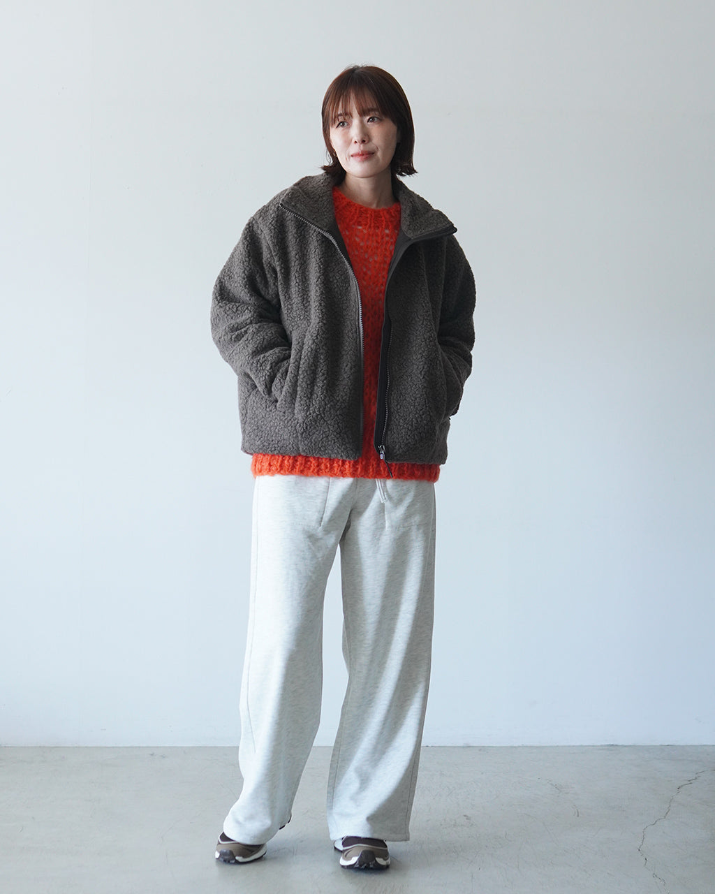 モヘア混のざっくり編みが特徴的なREEVES SWEATERの前面。ダークグレーのジャケットの下に、オレンジのニットが覗くレイヤード風の着こなしが映る写真です