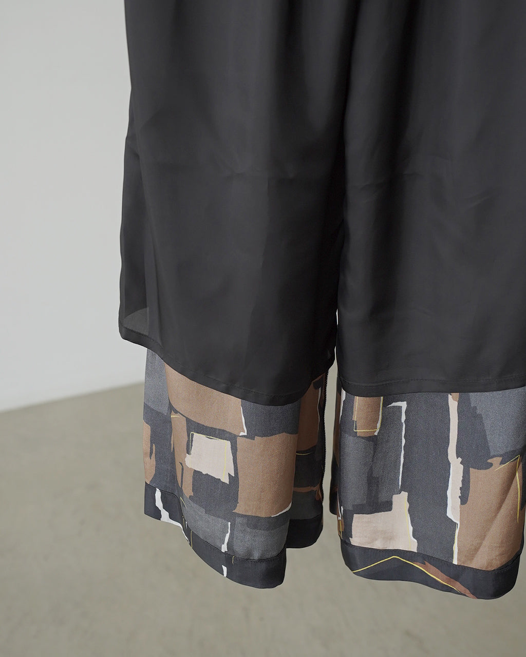 ブラックのGeometric Painting Pantsの裾と下部のトリムが見える裏地のイメージ。とろみのある生地の落ち感とワイドパンツのシルエットが伝わるディテール写真。