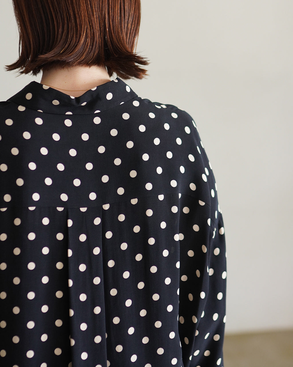黒地に白のドットが散らばるPOLKA DOT'S SHIRTの後ろ姿。襟元と背中のヨーク部分が見える、ゆったりとしたシルエットのシャツカラー。