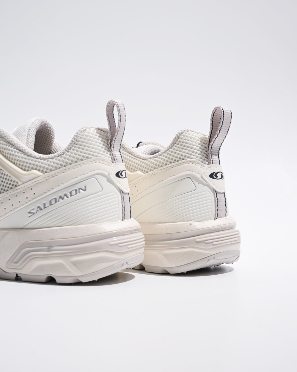 Salomonのホワイト系スニーカー、後ろ半身のディテールが見える写真。厚みのあるソールとサイドのロゴ、メッシュ素材の質感がわかる。