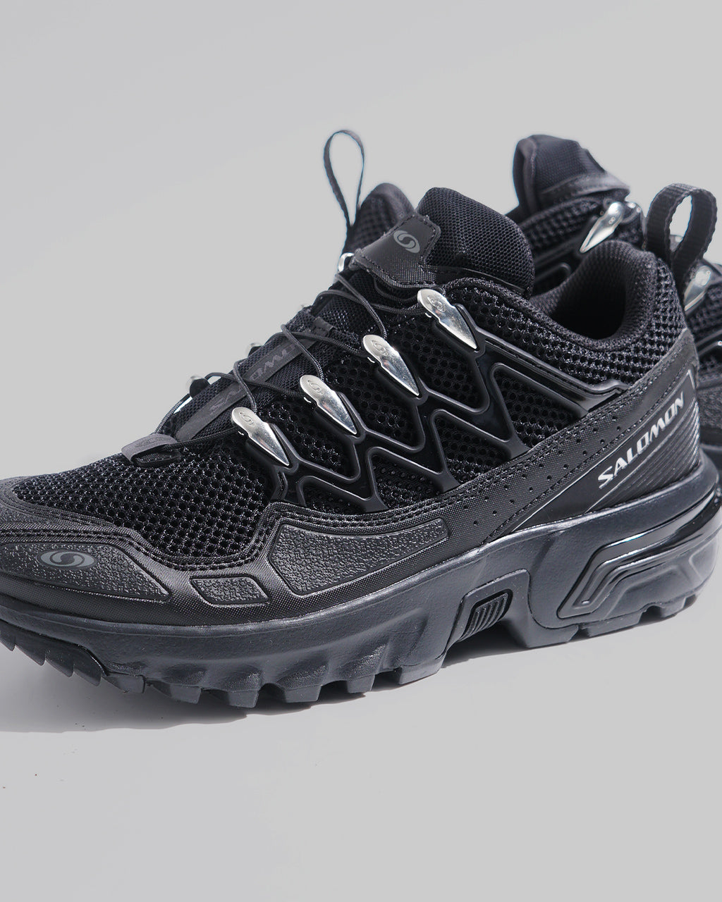ブラック系のアッパーが特徴のSALOMON ACS+ シューズ。前方からのアップでは通気性の高いメッシュとシルバーの固定パーツが見える