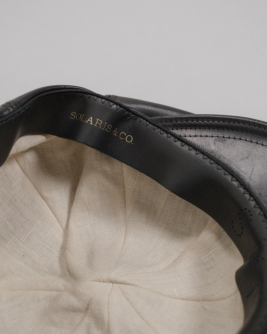 HORSEHIDE CASQUETTE / OLDBOY V01005 ブラックの帽子、内側はベージュの生地で、ブランド名 SOLARIS&CO. が型押し風に金色で刻印されています