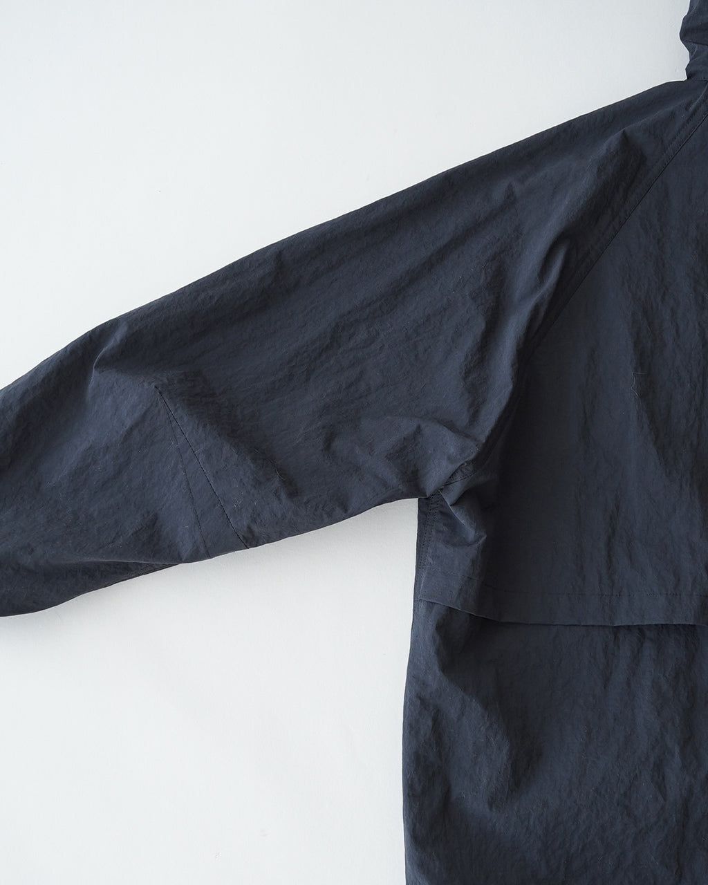 STILL BY HANDのCrispy hooded blousonの正面位置から撮影された navyブルーの撥水ナイロン生地のフード付きジャケット。袖を広げた状態で風合いと立体感が分かるショット