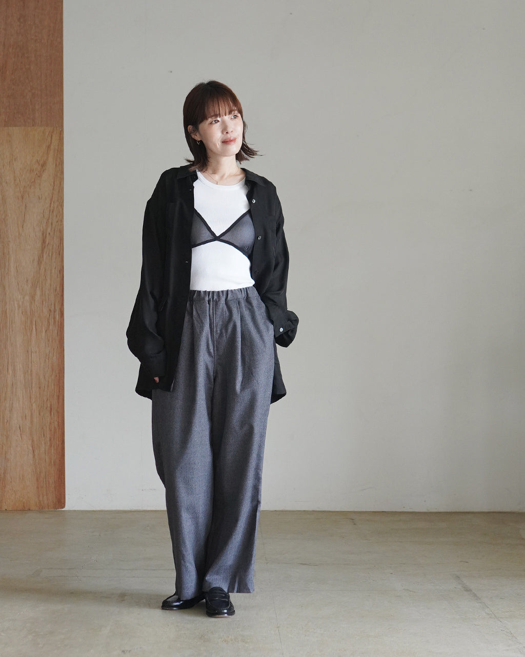 モデルが着用するウォッシャブルウールのパンツ。グレー系の落ち着いた色味で、ウエストはデザイン性のあるイージー仕様。裾までストンと落ちるリラックス感のあるシルエットが特徴。
