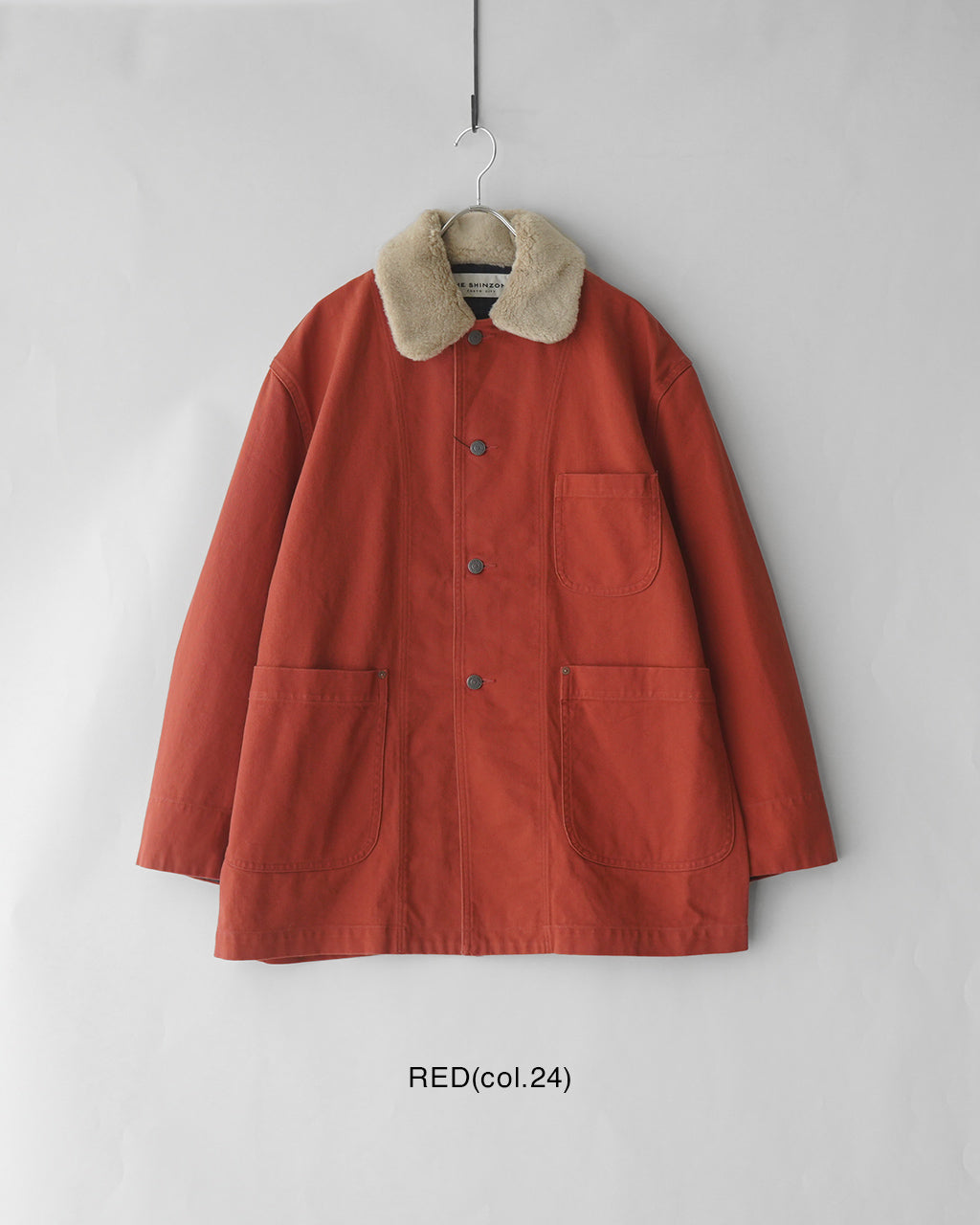 ブランドのTHE SHINZONEのベイク帆布ジャケット。赤みのあるカラーで、襟はボリューム感のあるファー風素材。前後に配置されたポケットとエルボーパッチ風の縫い目が特徴的なバージョンで、全体はオーバーサイズのゆとりあるシルエットです。