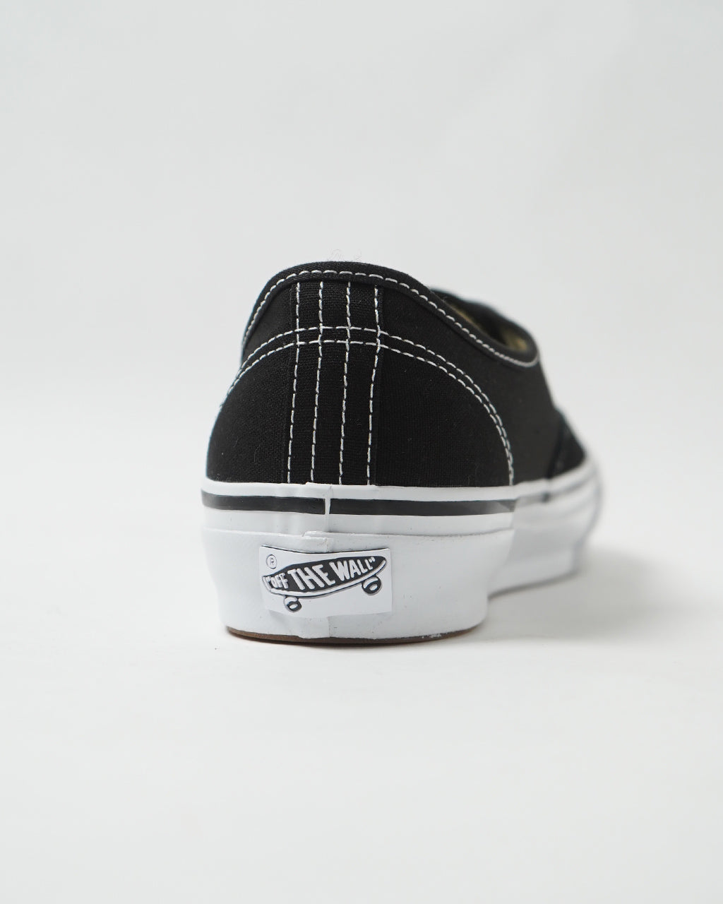 黒キャンバス地の後方から見るVANS LX Authenticの背面。白いステッチとトリムが際立ち、ブランドロゴ入りソールが特徴的