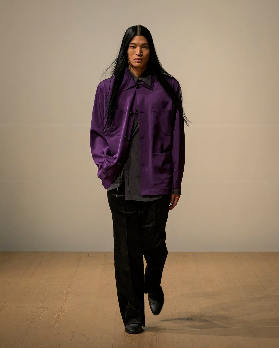 紫紺のSUPPLE WORK SHIRTを羽織ったモデルが前方へ歩く様子。光沢感のある生地とゆとりあるシルエットが特徴的な着用イメージ
