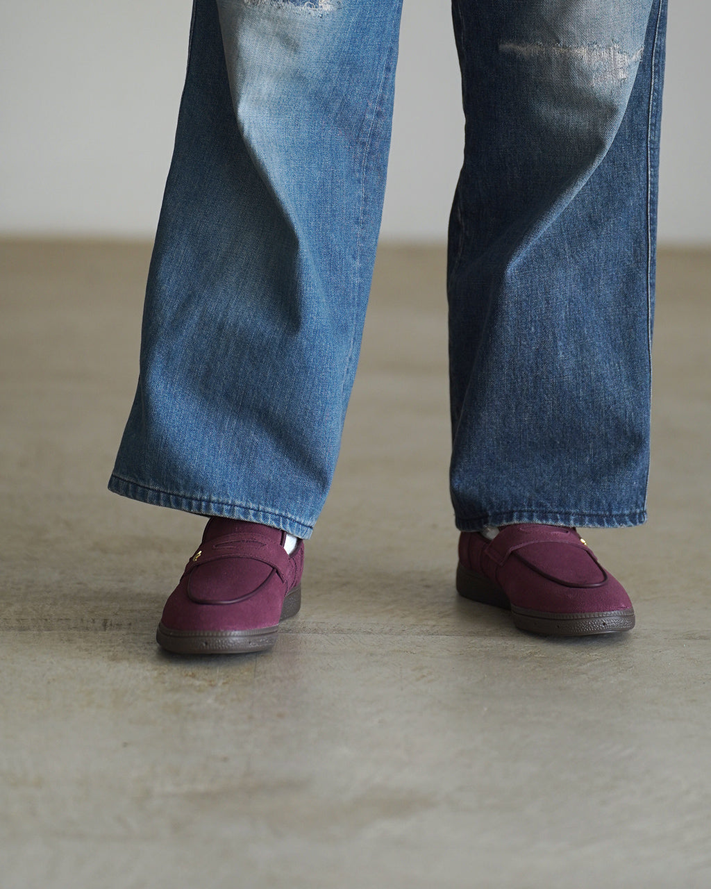 アディダス オリジナルス HANDBALL SPEZIAL LOAFER の前方ショット。ジーンズとボルドーのスエードローファーが視認でき、つま先周りとソールの配置がわかる構図です。