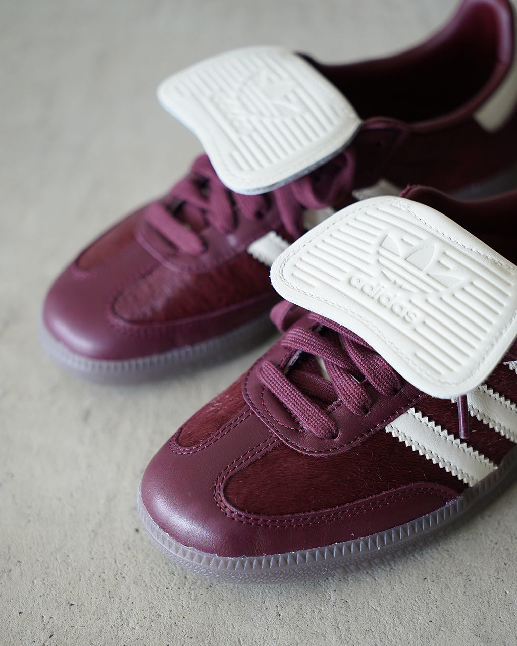 深めのパープルカラーのAdidas Samba LTのアップ。白いシューレースガードと白い三本ラインが際立つ、革素材の質感がわかる接写。