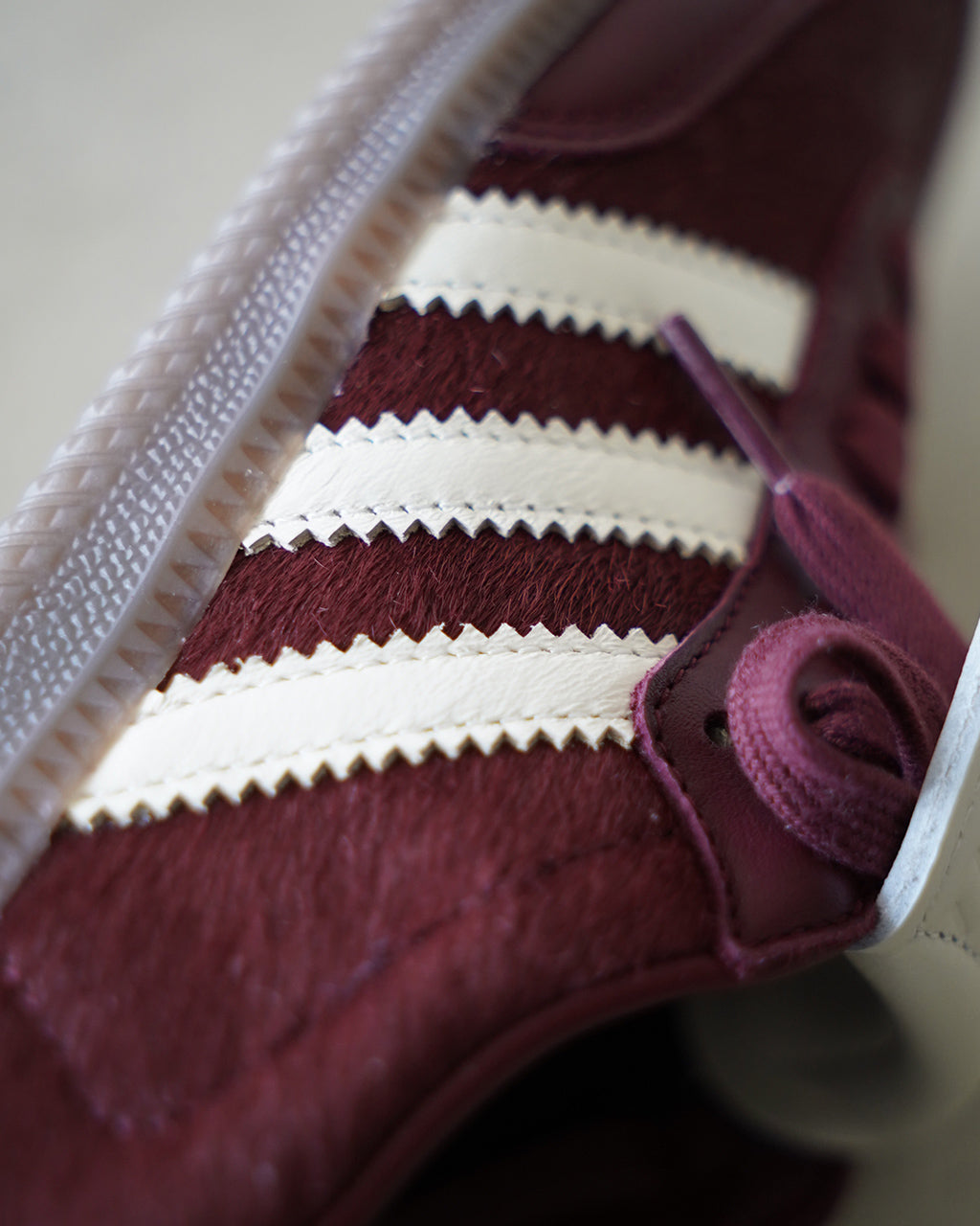 深赤色のスエード地に白い三本ラインを沿わせた adidas originals SAMBA LT の側面アップ。白いステッチやシューレースのディテールが際立ち、ラバーソールの質感も見える。
