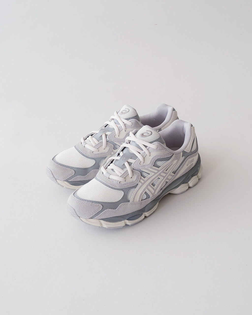 ASICS GEL-NYC の白と淡いグレーのランニングシューズ。メッシュとスエード風素材で構成された前後ソールが特徴的なデザインです