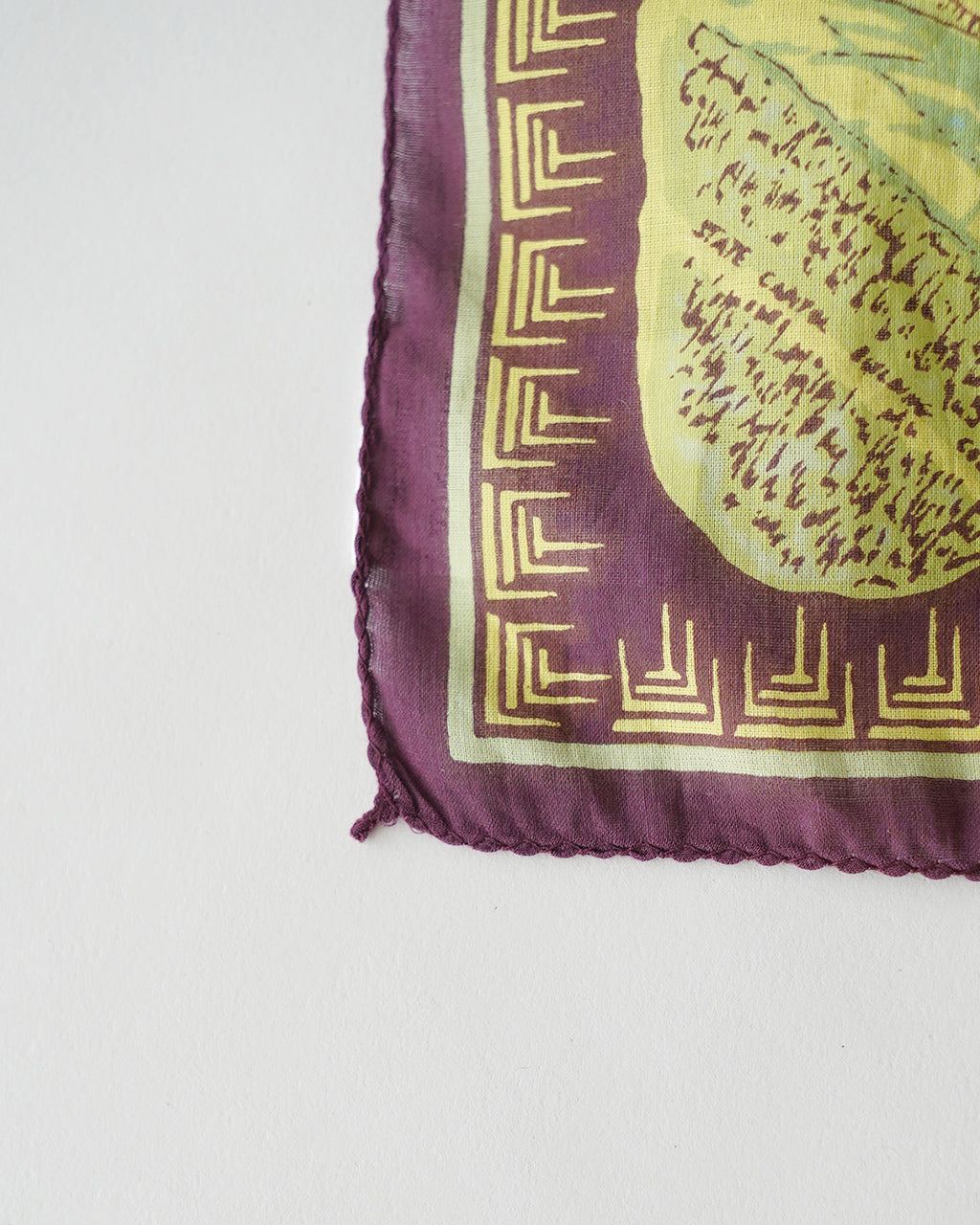 Ohio Bandana 50×50cmの端が折り返された縁と紫色の縁取りが見えるデザイン。中心には多様な色味のパターンがプリントされた正方形の大判ストールの一部。