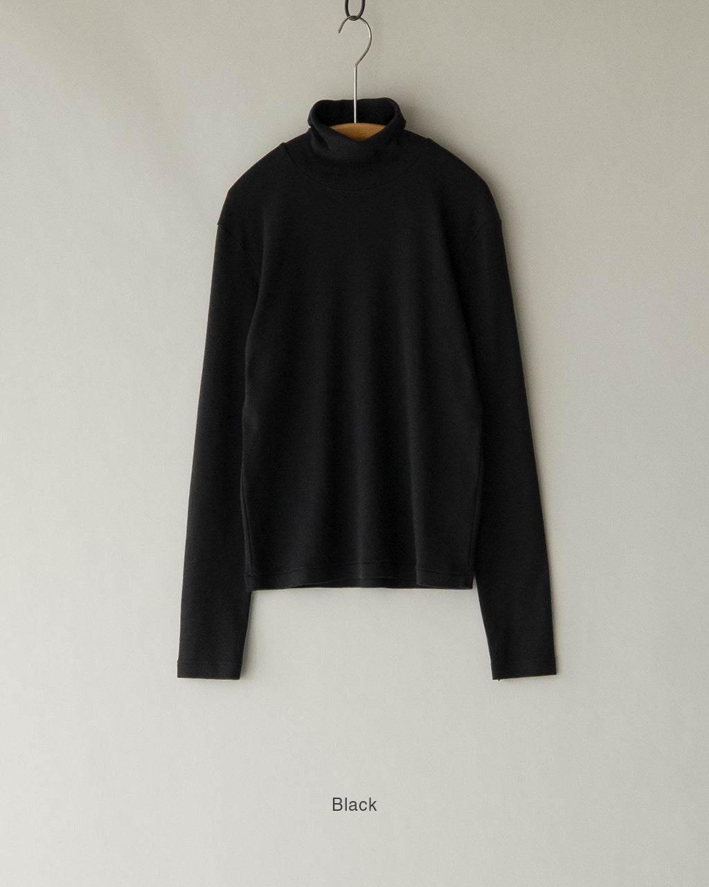 黒のタートルネック長袖Tシャツがハンガーに掛かり、シンプルなリブ編みと高密度の生地感が際立つ前面ショット