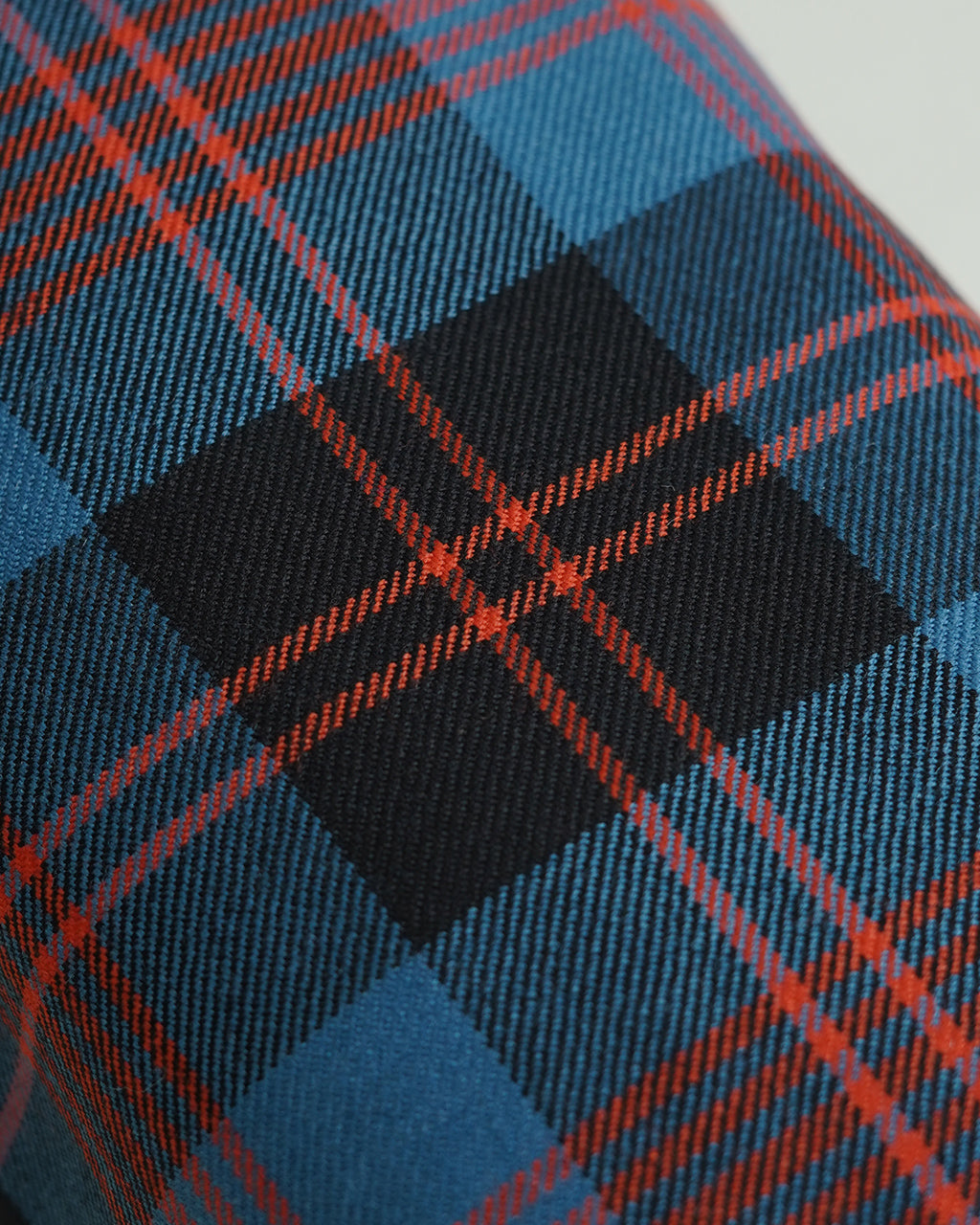 ブレディ KEER LOCHCARRON WOOL CHECKの生地アップ。赤と黒のタータンチェックとブルー系の背景。ウール素材の織り柄が分かる接写。