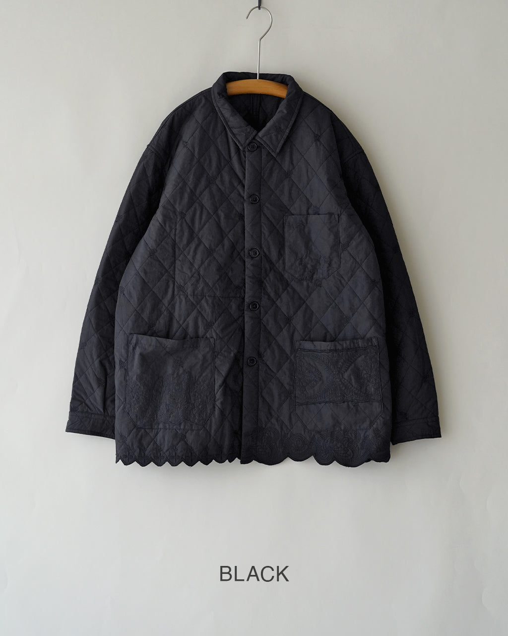 黒い刺繍キルティングジャケット。正面中央にボタン留めと胸ポケット、下部には左右にポケットがあり、裾にクラシカルなスカラップが施されています。