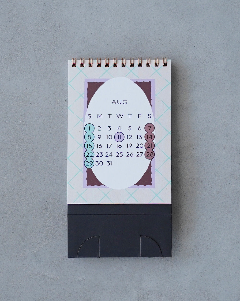 幻日堂のFrames Desk Calendar、卓上に置かれた小型カレンダー。表紙は幾何学模様と大きな白い円形、色使いは淡いパステル系でデザイン性が高い
