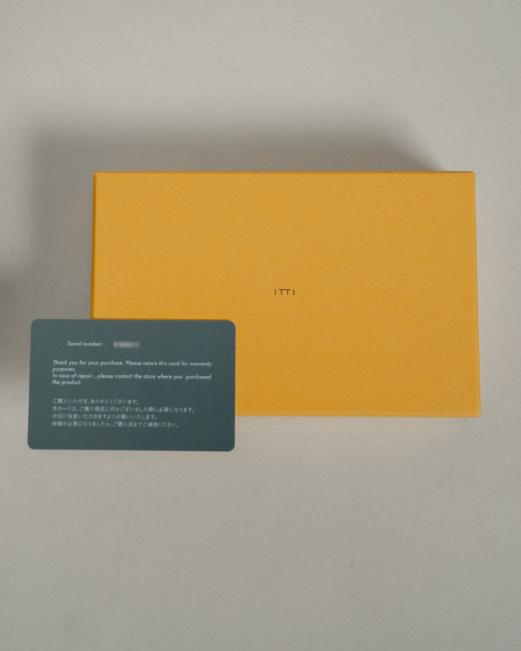 イッチ ITTI Cristy Wind Smart Mid Wallet Croco クロコダイル型押しの財布が、オレンジのボックスとカードで前面に配置された写真