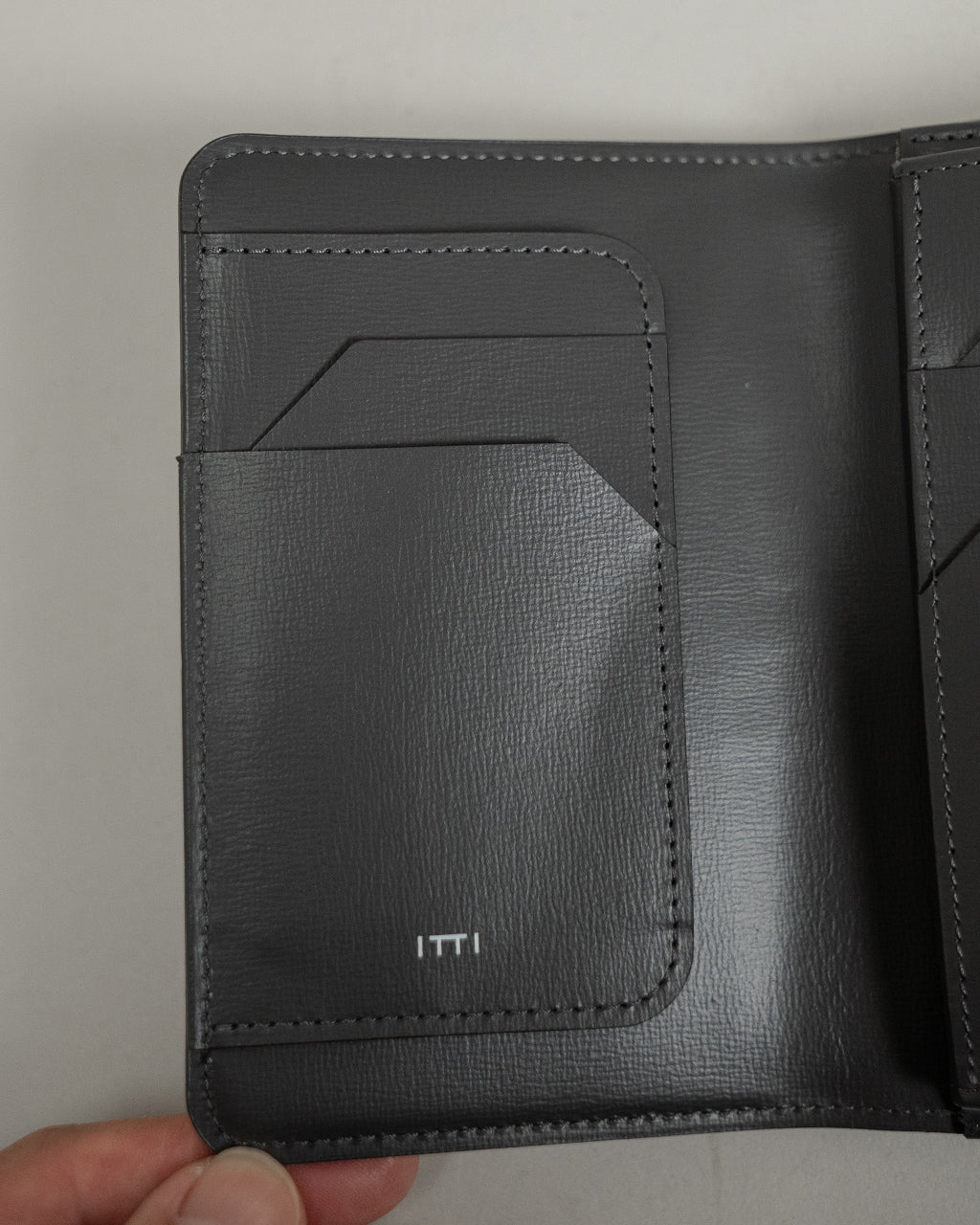 ITTIのブラックレザー製ミッドウォレットの前面ポケット部分。繊細なステッチと立体的なカードポケットのデザインが際立つアップ画像。