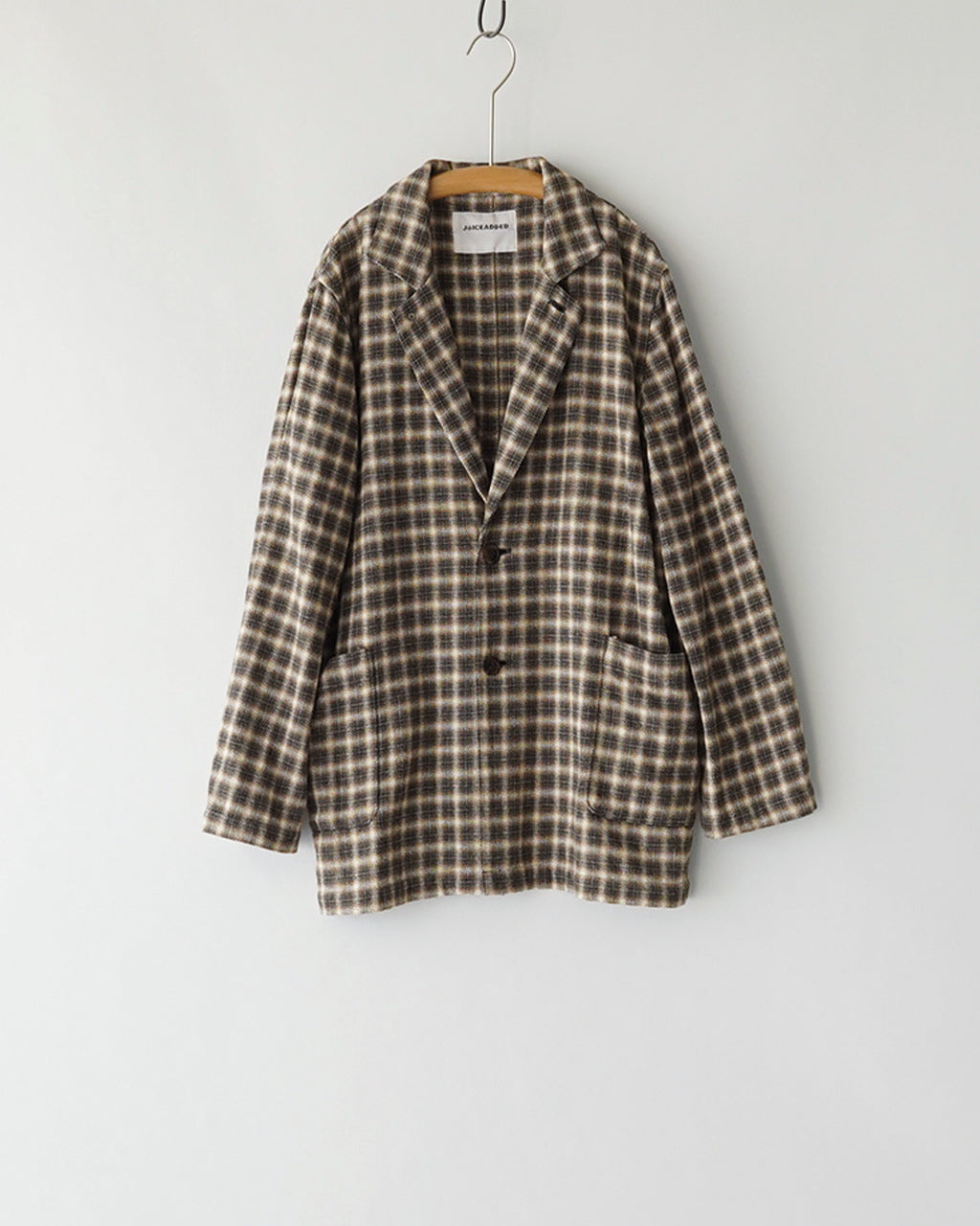 Brown-Check柄のジャケットがハンガーに掛かっている前面ショット。ゆったりとしたシルエットとブランドロゴの形が分かるデザイン画像。