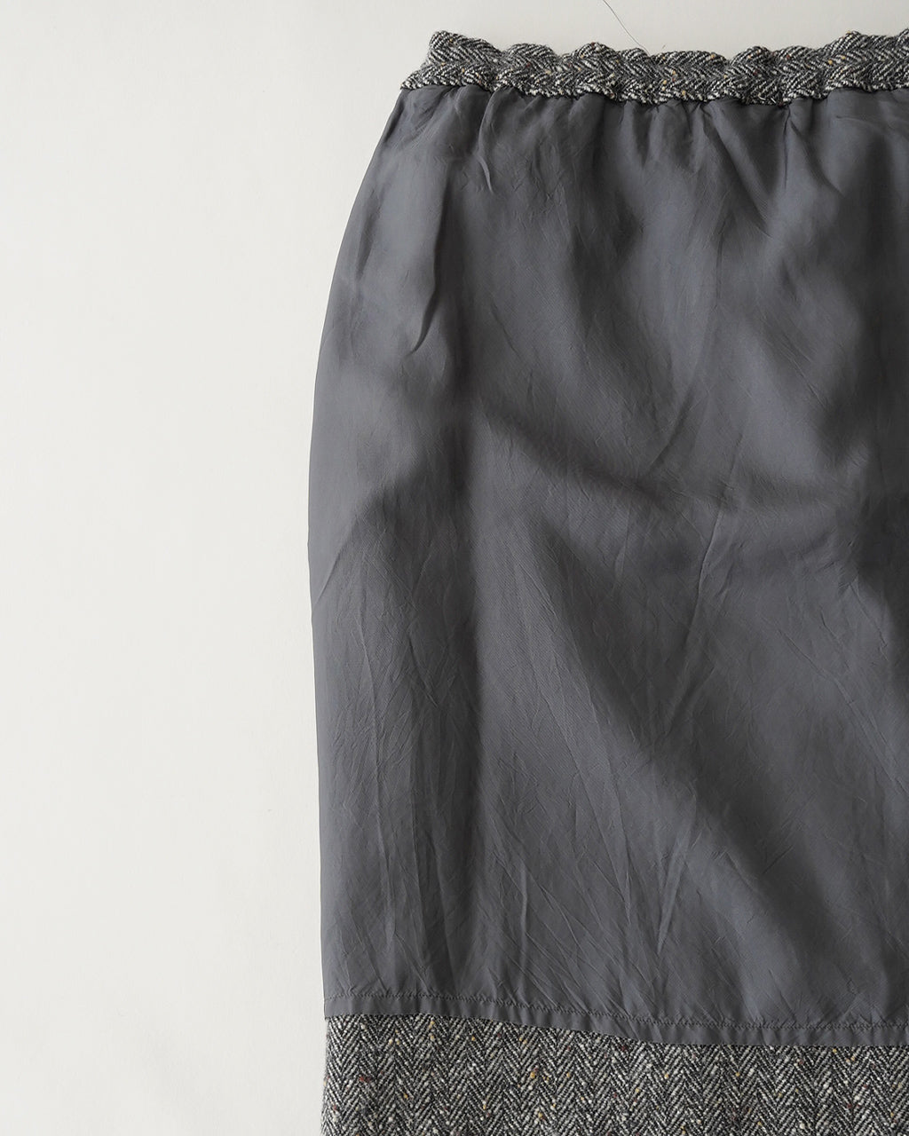 ヘリンボーン生地とウエストゴムの Mood Pencil Skirt。上部は絞りのあるブラック系のシャープなラインが特徴で、裾は別素材のマルチカラーのヘリンボーン生地が切り替えられている。