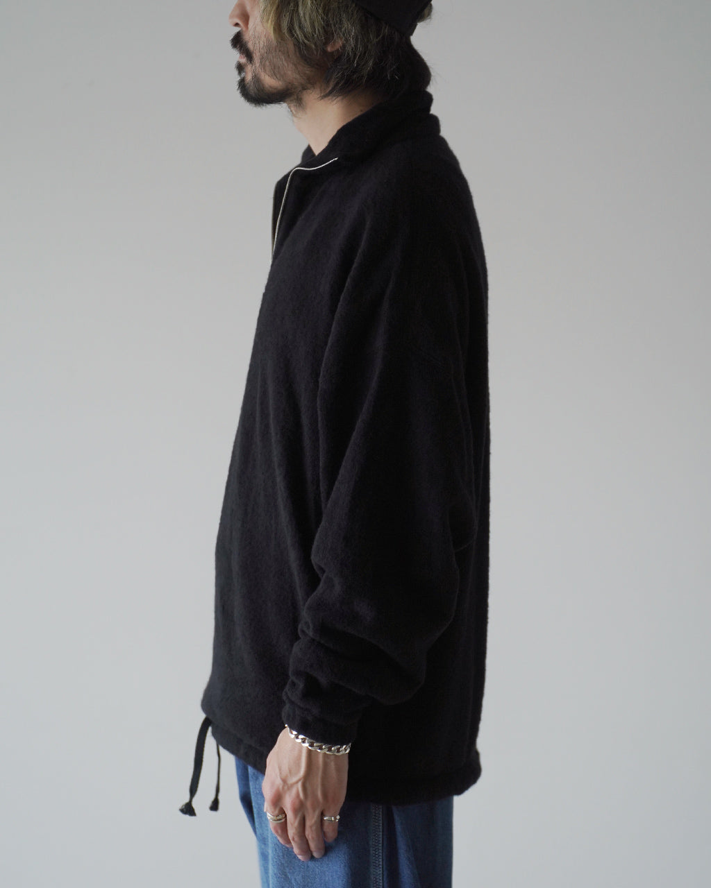ブラックのSilk Wool Fleece Pulloverを横から撮影。高めのスタンドカラーとハーフジップが見え、ボディはゆったりとしたシルエットで袖口はリブ仕様。
