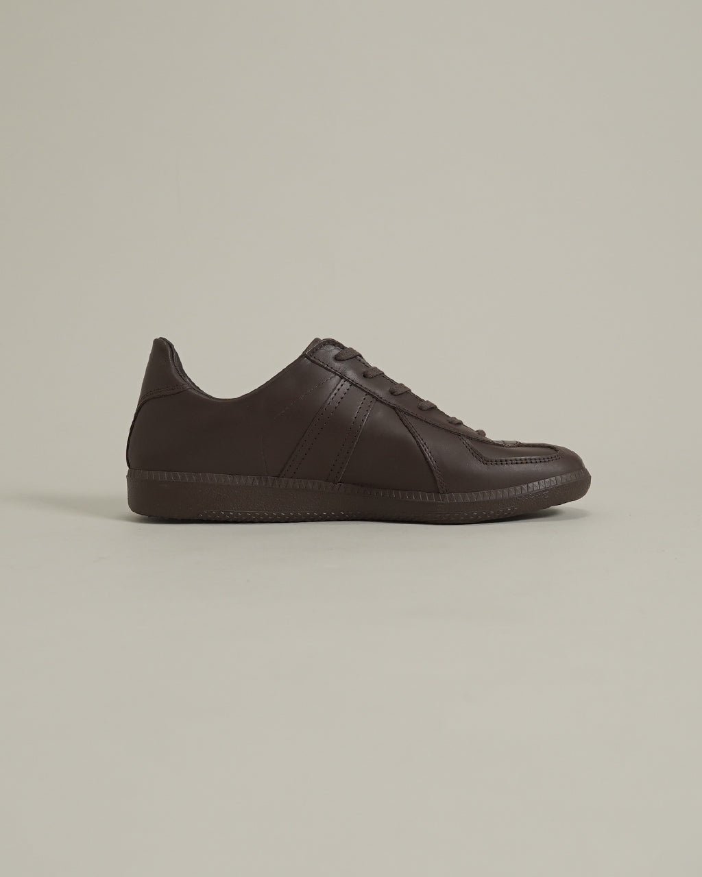暗めのブラウン系レザーのジャーマントレーナーを横から見る。滑らかな質感のアッパーと一体感のあるソール、シンプルなステッチが特徴。