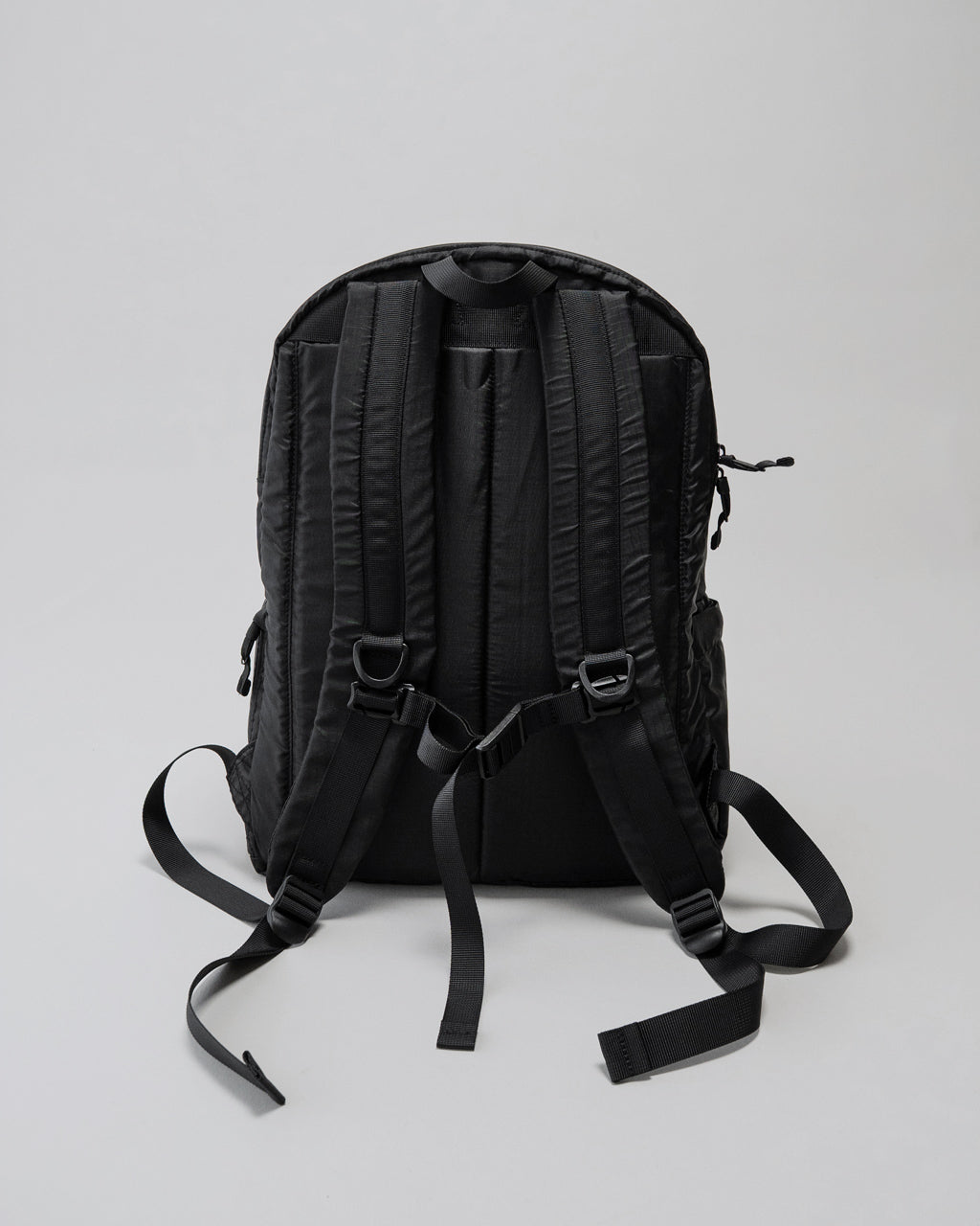 LC by LOWERCASEのバックパック背面ショット。黒色の20L容量モデルで、肩と腰ベルトのパッドが厚く、背面ファスナー部の構造が見える。