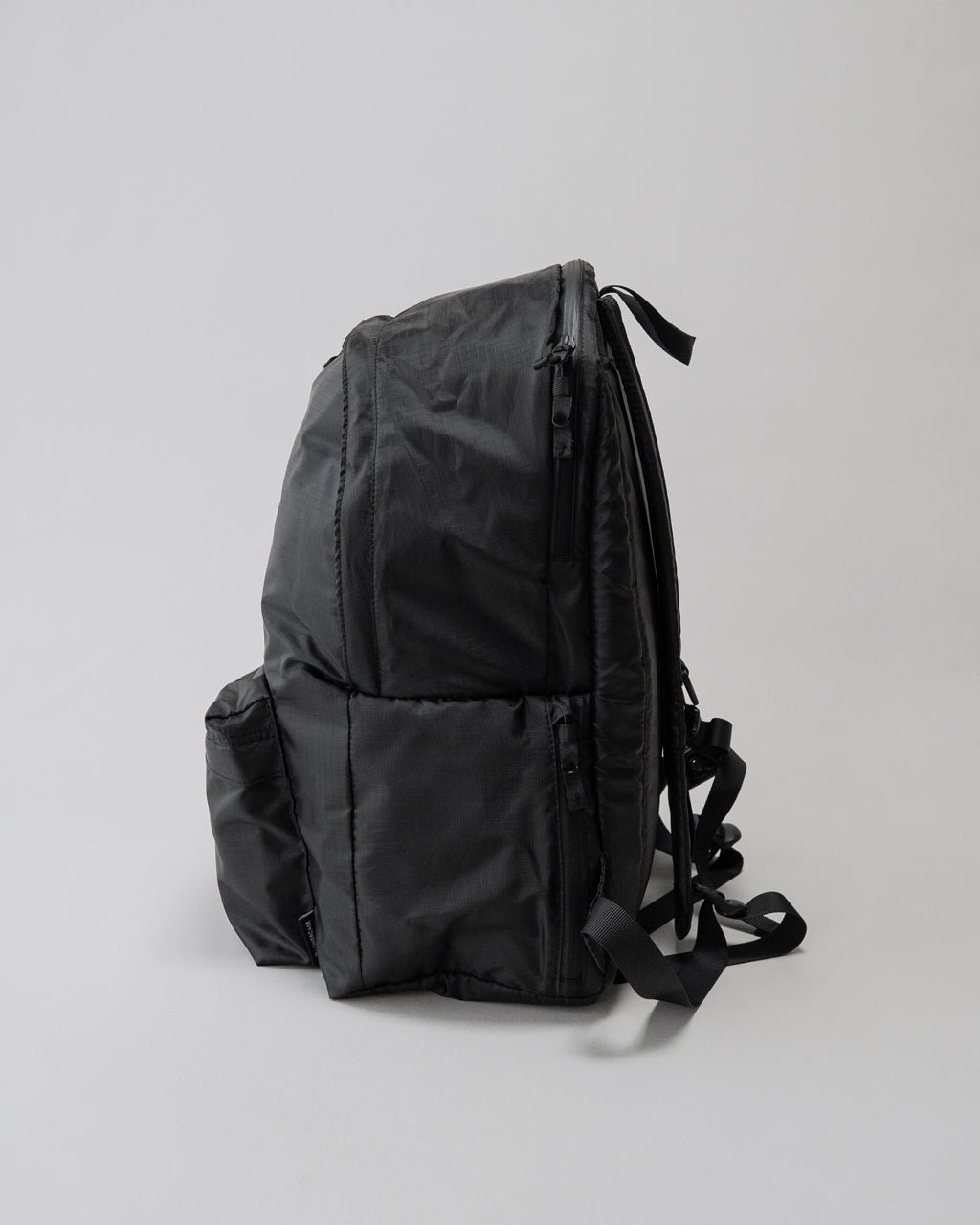 LC by LOWERCASE の DAYPACK LITE 30Lの側面と背面が分かる黒のリュック。側面ポケットやショルダー部分、ファスナーの仕様が見える。
