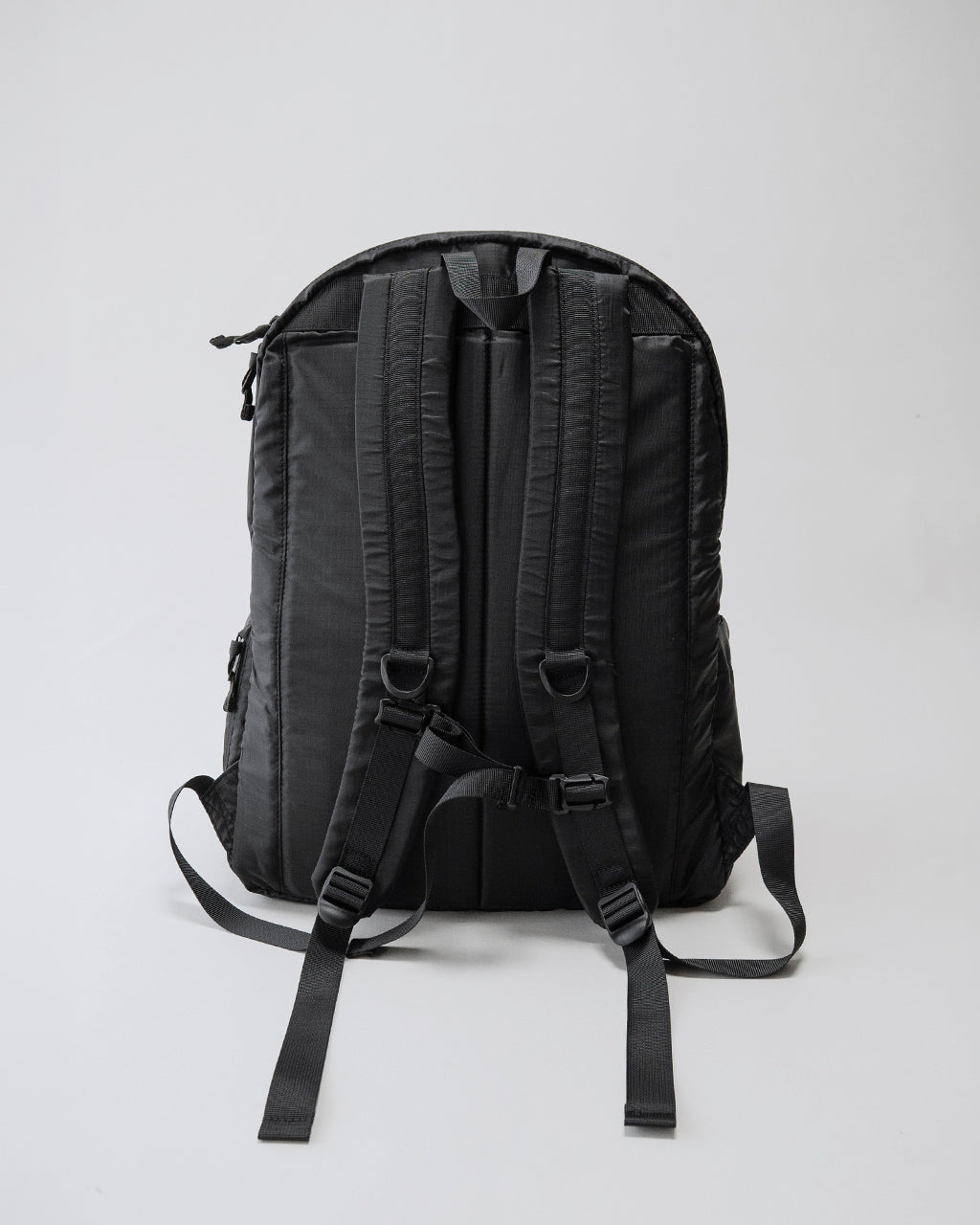 LC by LOWERCASEのDAYPACK LITE 30Lの背面ショット。黒系のバックパックで、ショルダーストラップと背面パッドの設計が見える。シンプルなリュックの形状を確認できる画像。
