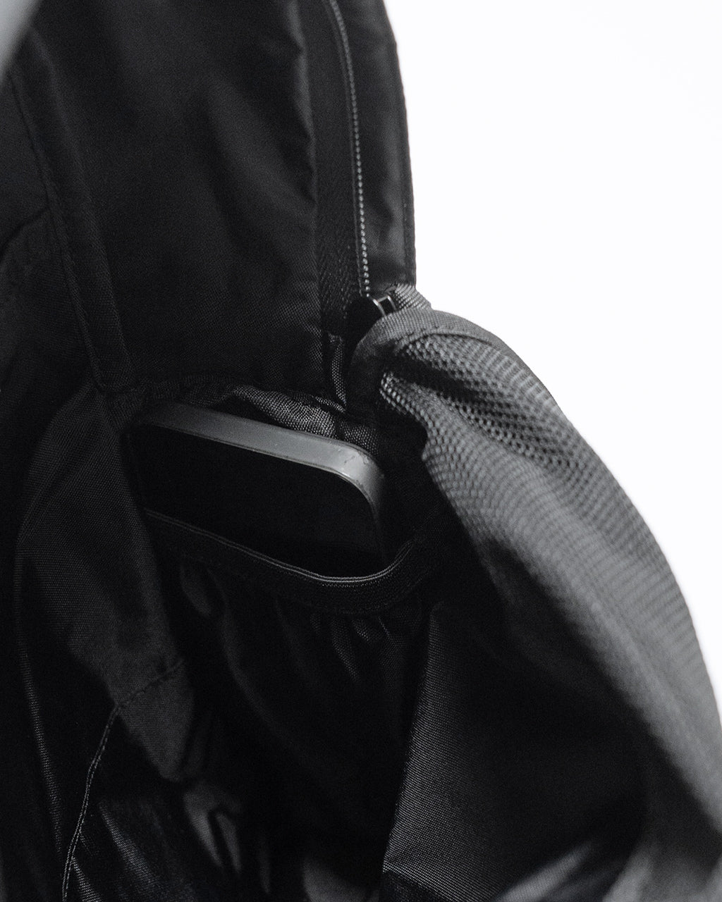 LC by LOWERCASEの DAYPACK LITE 30Lの内側ポケットとファスナー周りの拡張ディテール。黒色系の生地と柔らかい布地感が窺えるショルダーバッグ型リュックのアップ写真