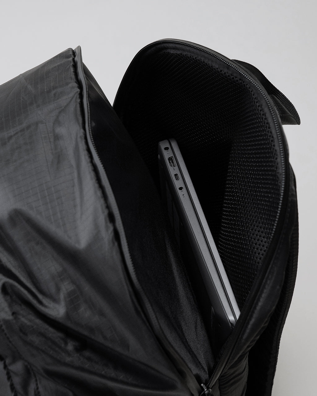 LC by LOWERCASEの DAYPACK LITE 30Lの前面と側面のファスナー開閉部が見える黒色リュック。耐久性のありそうなナイロン素材とコンパクトな設計が分かるディテールショット。