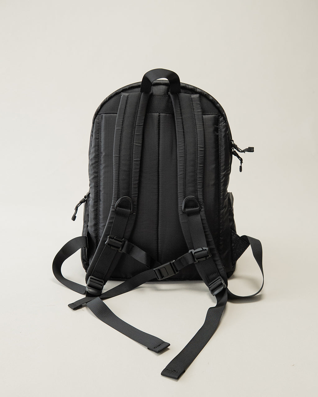 LC by LOWERCASE の Daypack Lite 16L。背面とショルダーストラップが黒色で、背面パッドと複数のベルト付きのバックパック正面を背面から撮影した全体像。