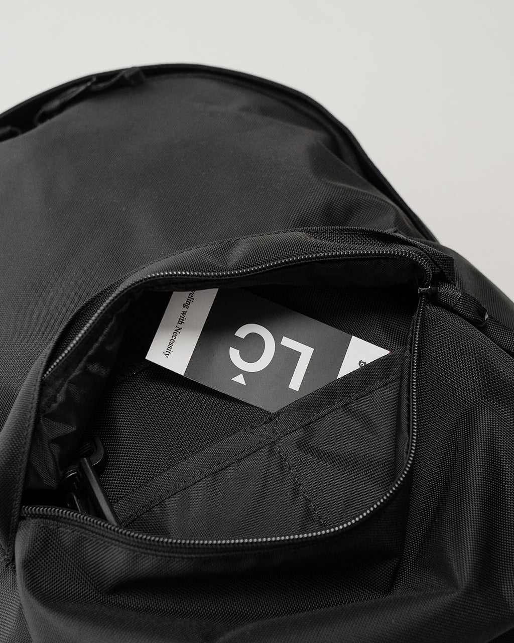 LC by LOWERCASEのDaypack 16Lの内側ポケットを開いた状態。黒色のナイロン生地とジッパー、ブランドタグが見える。