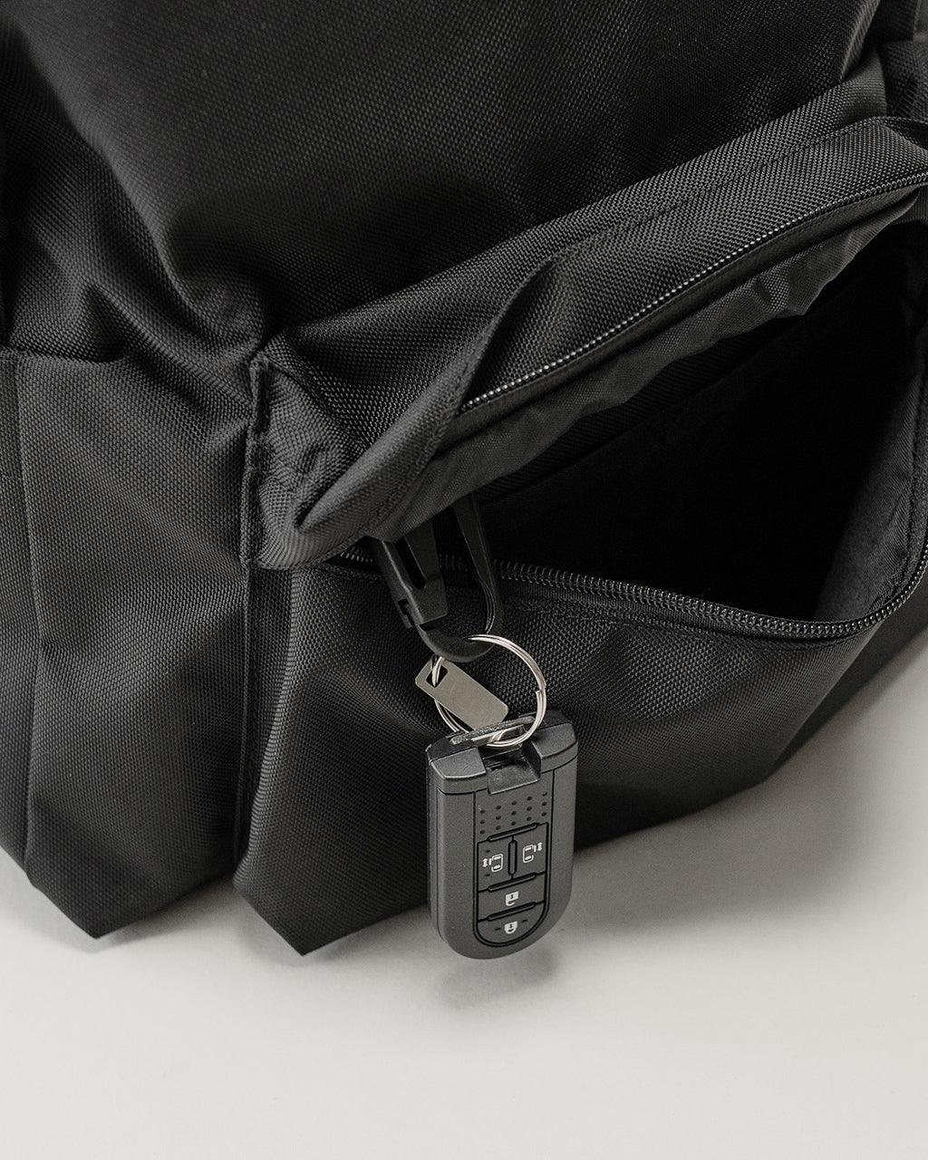 LC by LOWERCASEのバックパック、黒系の素材感が際立つオープンポケットとジッパー、鍵付きセキュリティ用ファスナーが見える正面ディテール