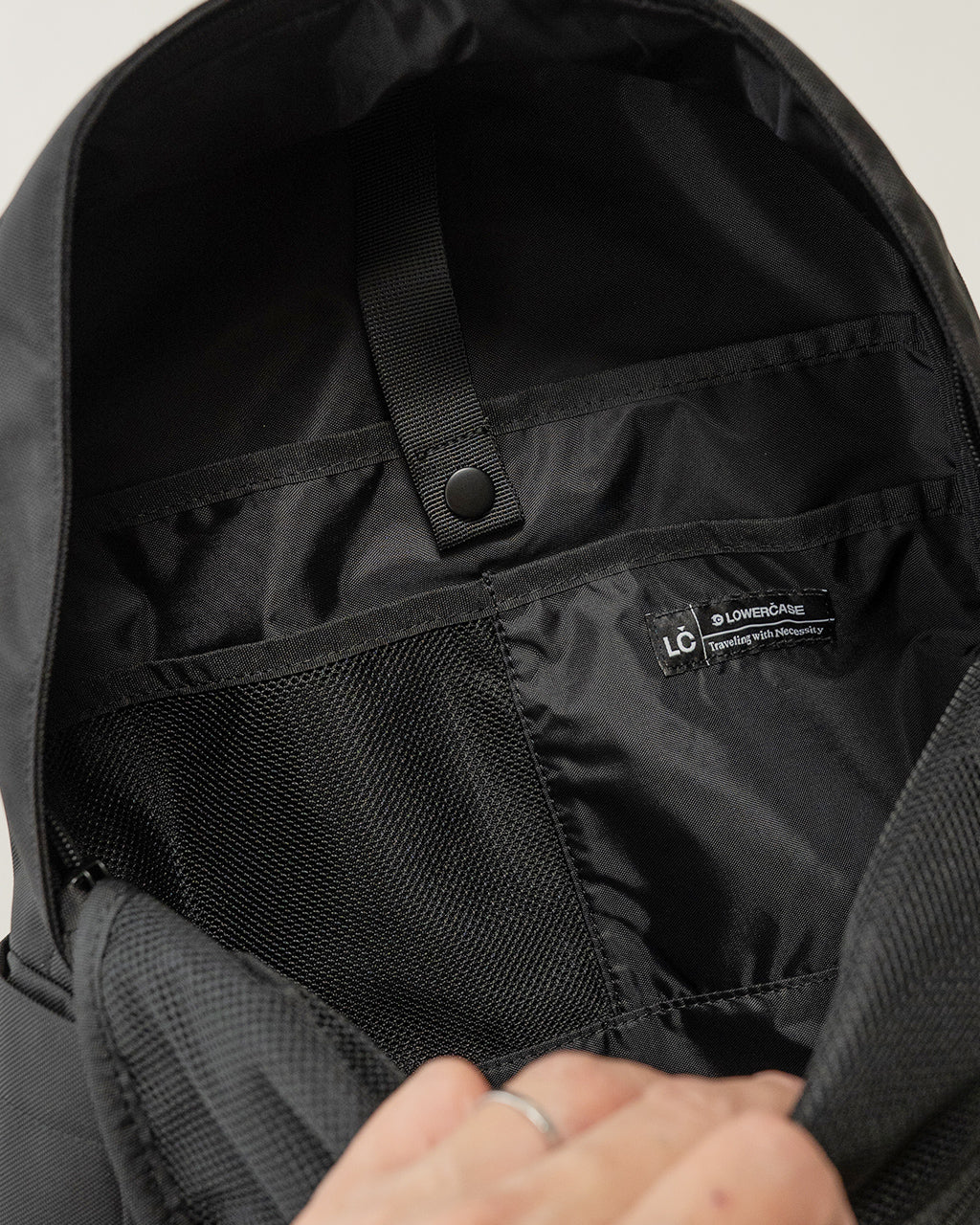 ブラックのLC DAYPACK STANDARD 16Lの内部を上から見たショット。内ポケットと固定ベルト、ロゴタグが見えるシンプルな収納部の様子。