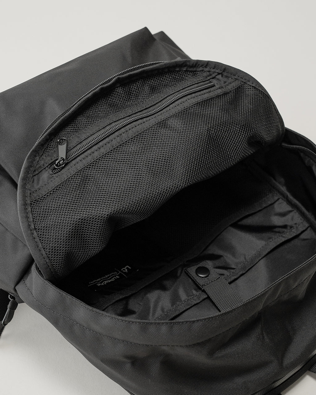 LC by LOWERCASE の DAYPACK STANDARD 16L の内部ジッパー付きポケットとメッシュ生地の背面部分が見えるブラックのバックパック