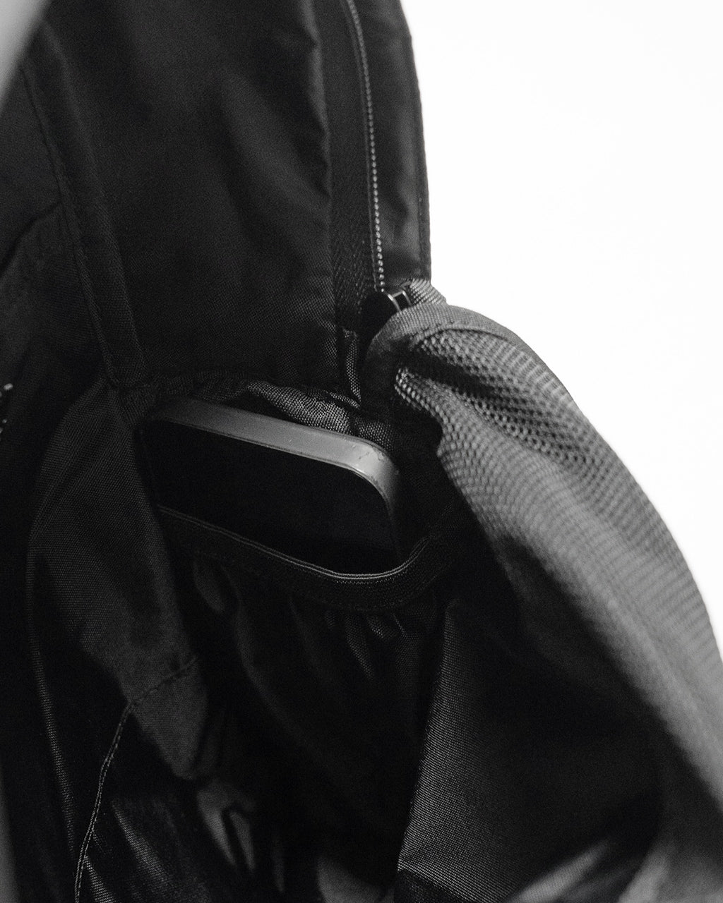 LC by LOWERCASE の DAYPACK STANDARD 16L の内部、スマホが収まるポケットとシンプルな仕切りを持つ黒色バックパックの開口部近影