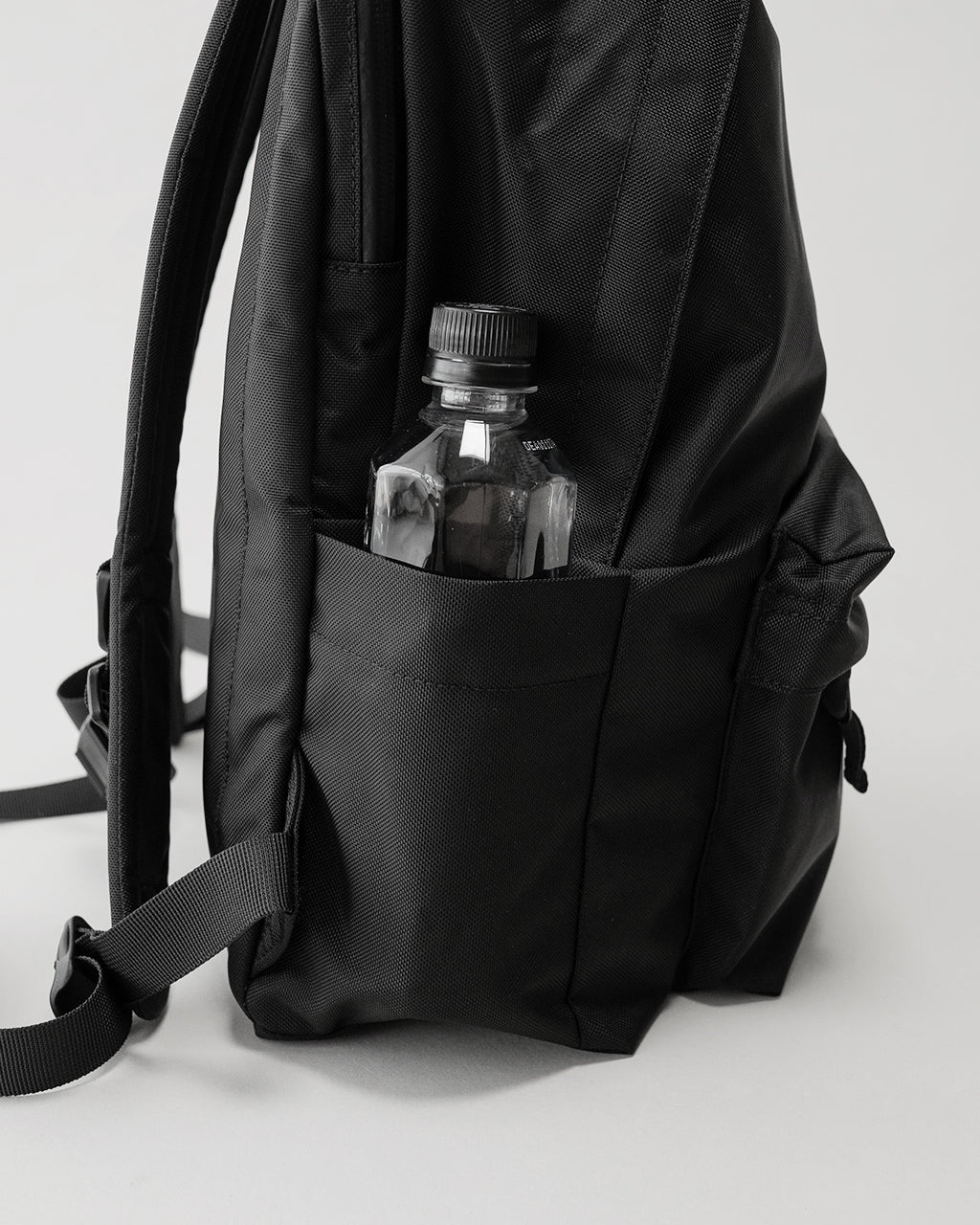 LC by LOWERCASE の Daypack STANDARD 16Lの側面ショット。背面ポケットに水筒を収めた黒色ナイロン製リュックサックの細部が見える。