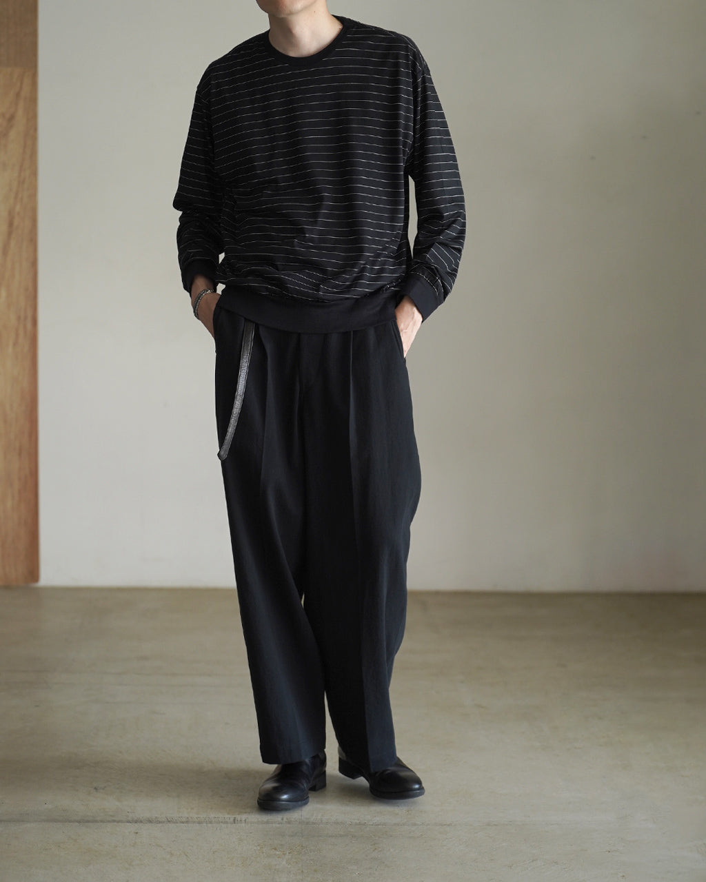 ブラック地に細い白いボーダーが入ったクルーネックの長袖Ｔシャツ。リブ付きの裾と袖口がカジュアルな雰囲気を引き締め、ゆったりとしたシルエットが特徴的です。