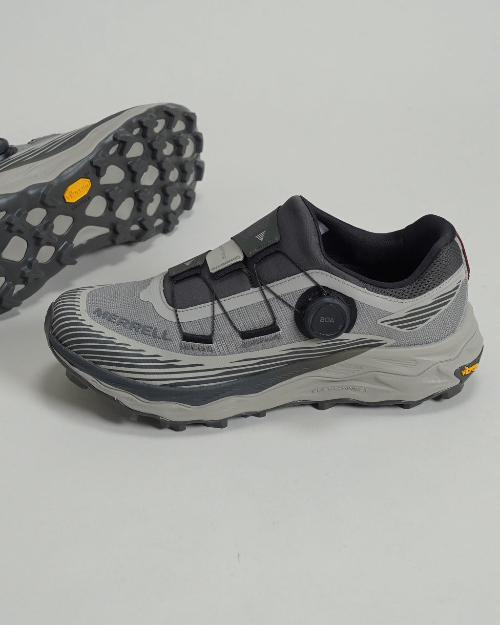 グレー系のトレイルランニングシューズ、BOAダイヤルで締まり、ソールは凸凹のVibram MegaGripパターン。上部は層状のメッシュと合成素材で構成され、横から見たアウトソールの形状が特徴的です。