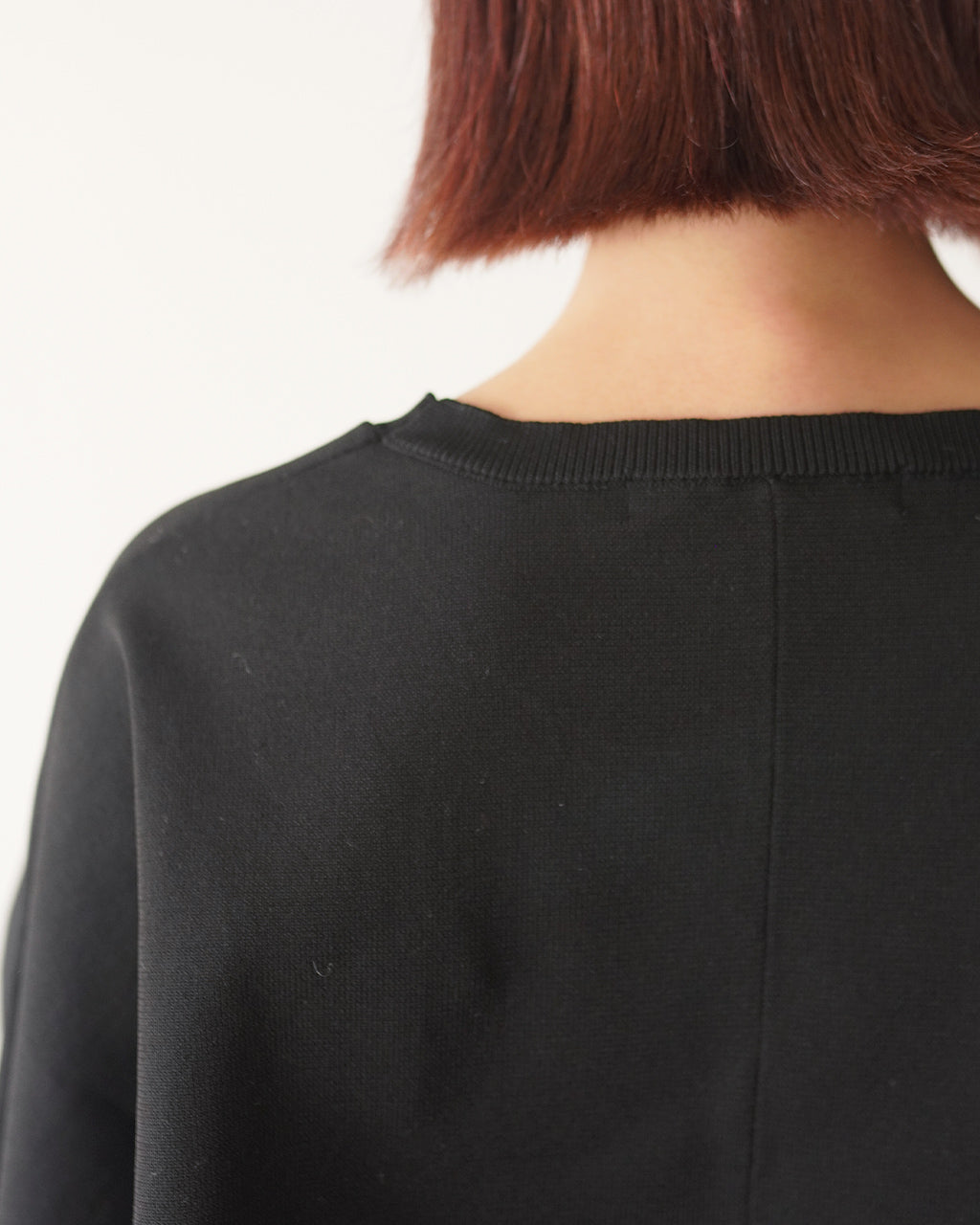 mizuiro indの cocoon P/O のバックショット。襟元と肩のラインが分かる黒のトップス、裾まで落ちるドロップショルダーのゆとりあるシルエットを確認できます。