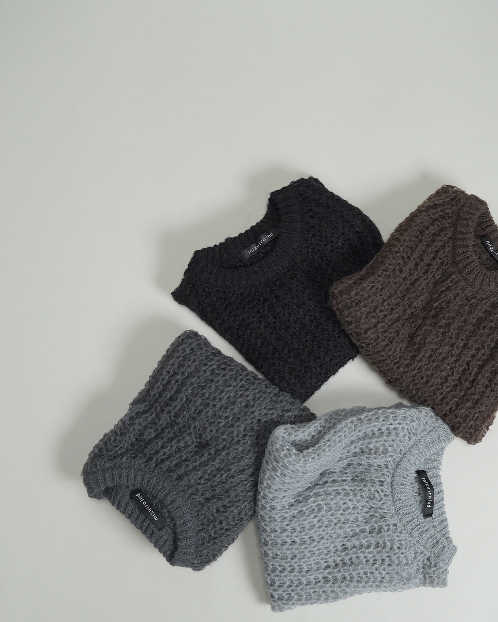 ミズイロインドの hairly cocoon wide vest が並ぶディテール。黒・グレー・ライトグレー・ブラウン系のニットベストを折りたたんだ状態で、ふっくらとしたボリューム感とコクーンシルエットが分かる画像