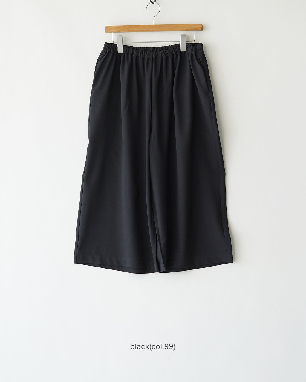 ウエストゴム×ゆとりのあるワイドシルエットのパンツ。黒系カラーの無地で、ハンガーに掛けられた前面全体像を捉えたデザイン画像。