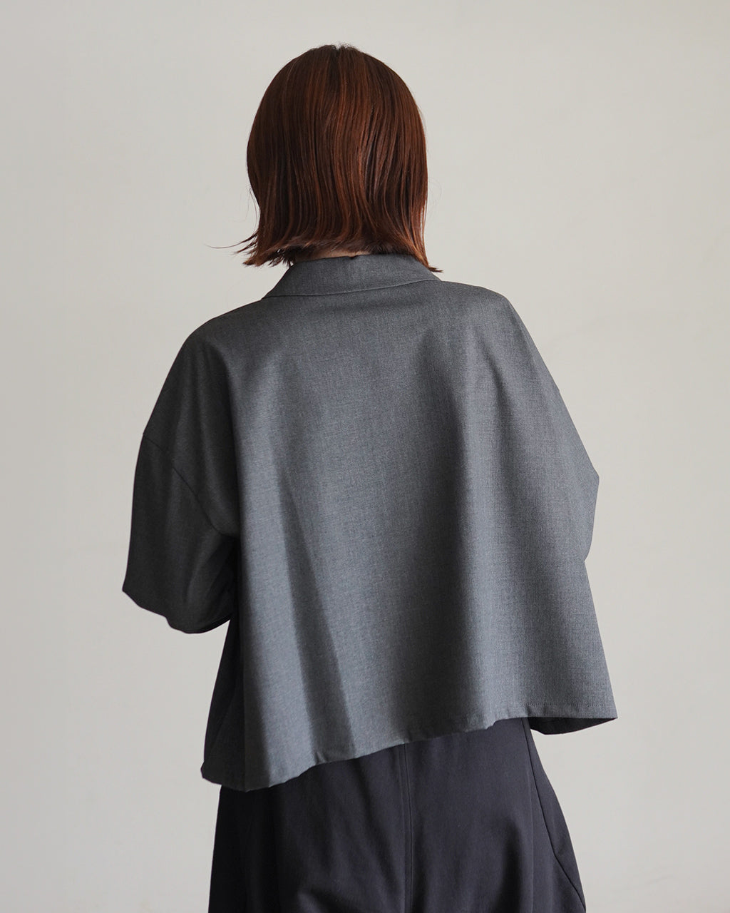 mizuiro indの wideシャツの後ろ姿。グレー系の落ち着いた色合いで、ゆったりとしたベル型の裾と肩のラインが特徴的なデザインが映る背面ショット