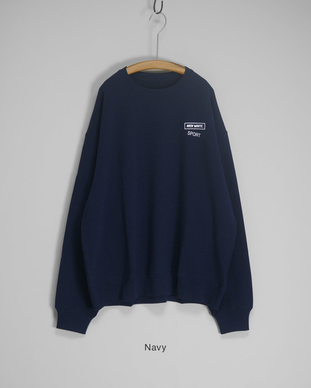 Navyのクルーネックスウェットシャツ。胸元にNICK WHITE SPORTのワンポイントロゴが配置されたシンプルなデザインの長袖トップス。